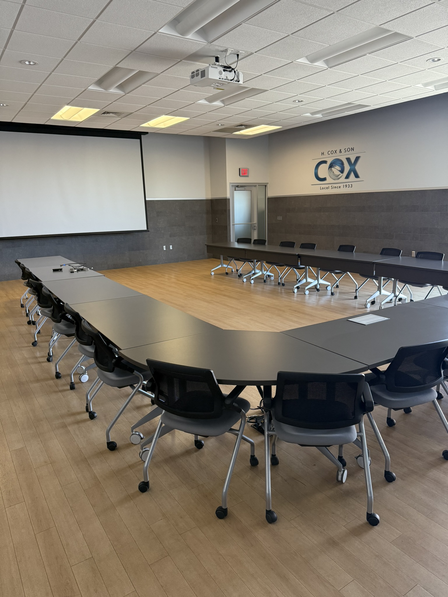Large conference room with H. Cox & Son branding and projector screen